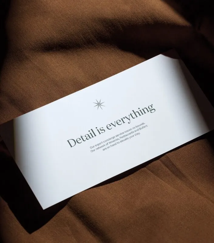 flyer card that says 'detail is everything' placed on dark brown luxury fabric